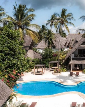 A pool area with thatched-roof structures, palm trees, and a clear blue pool. - Marafiki Beach Hotel & Spa (Matemwe)
