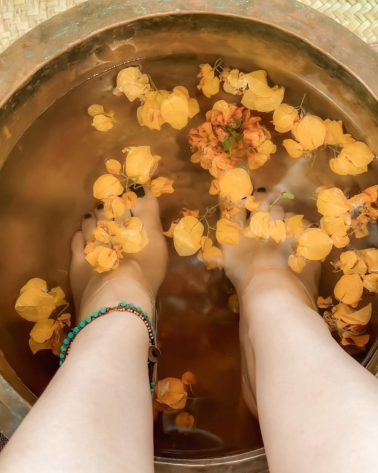 Una persona sentada en un recipiente con agua y flores amarillas.