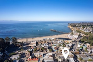 Vista aérea de un pueblo costero con playa, muelle y un denso conjunto de edificios.