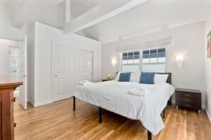 A bedroom with a bed, bedside table, and a window with curtains.