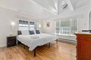 Un dormitorio con cama, mesitas de noche, cómoda y ventana con vistas.