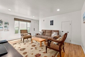 A living room with a sofa, two armchairs, a coffee table, and a TV.