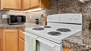Une cuisine avec des meubles en bois, un four à micro-ondes et une cuisinière blanche.