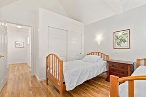 Ein Schlafzimmer mit zwei hölzernen Betten, einem Schminktisch und einer Tür zu einem anderen Raum.