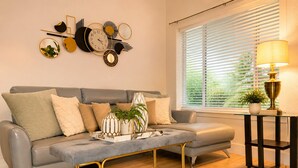 Una sala de estar moderna con un sofá gris, una mesa de centro con marco dorado y un reloj de pared.