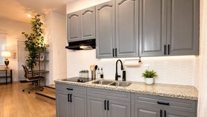 Una cocina con gabinetes grises, encimera de granito, grifo negro y pileta de acero inoxidable.