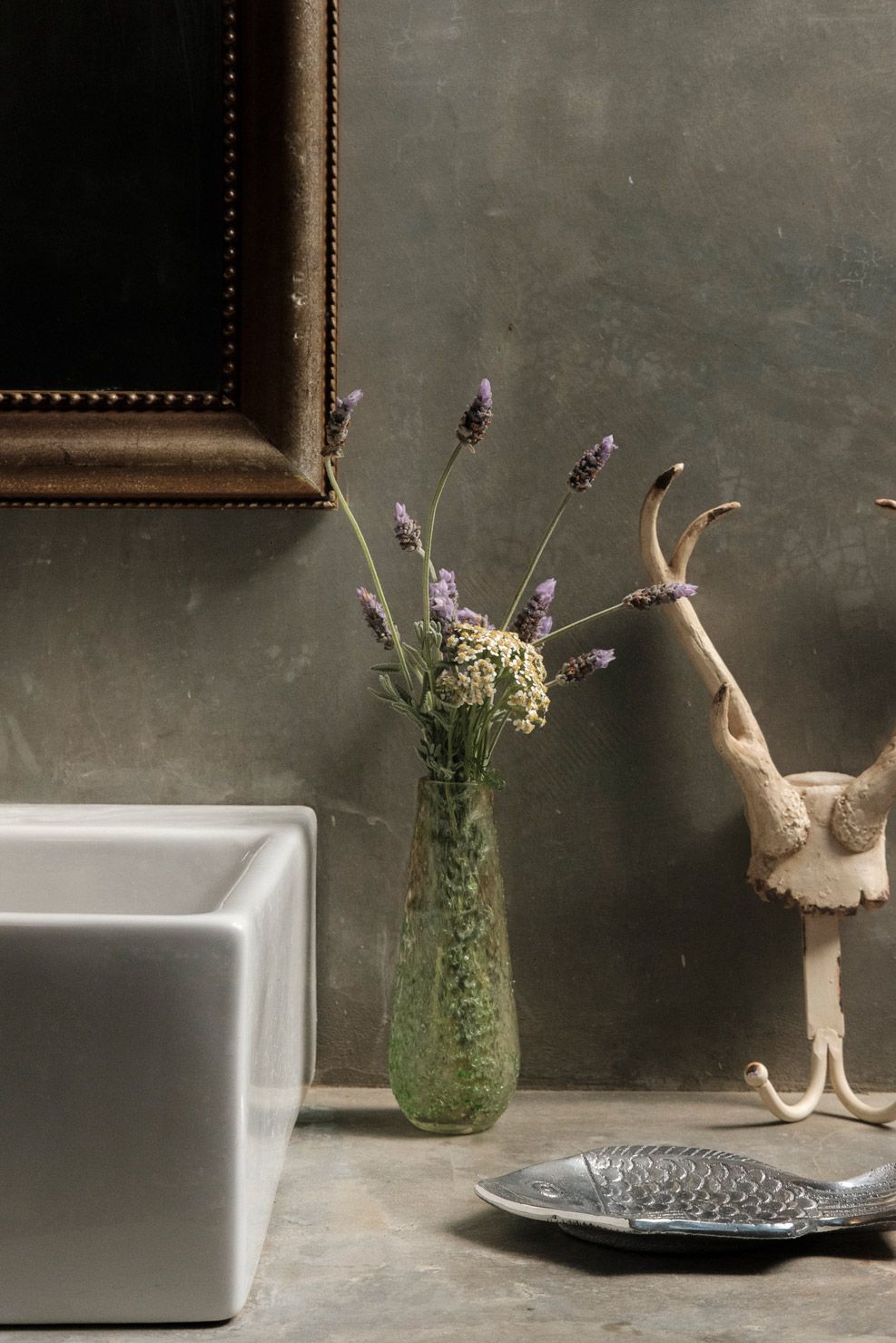 Un vase rempli de fleurs et une tête d’animal décorative posés sur une table.