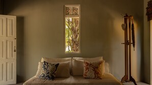 Un dormitorio con cama, ventana con vista a árboles y un atril de madera con un paraguas.
