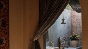 Un baño con lavamanos, espejo, objetos decorativos e iluminación colgante.