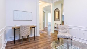 Une pièce spacieuse avec un plancher en bois, une table basse en verre et deux chaises.