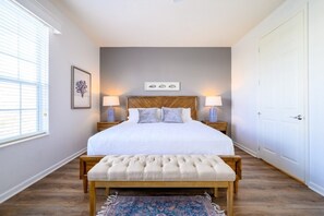 A bedroom with a large bed, bedside lamps, a bench, a rug, and a framed picture on the wall. - Vista Cay Electra 3 Bedroom Condo by RedAwning (Orlando)