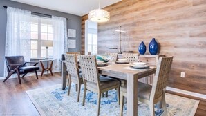 Un coin repas avec une table en bois, des chaises et un lustre.