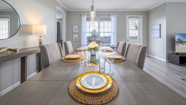 A dining room with a long table set for six, a chandelier, and a view of the city through large windows. - Vista Cay Lakeview Elysium 3 Bedroom Condo by RedAwning (Orlando)