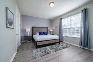 Une chambre à coucher avec un lit, des tables de chevet, un tapis et une fenêtre avec des rideaux.