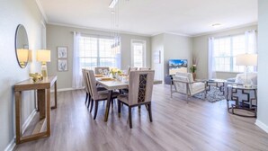 A spacious living room with a dining area, large windows, and modern furniture. - Vista Cay Lakeview Elysium 3 Bedroom Condo by RedAwning (Orlando)