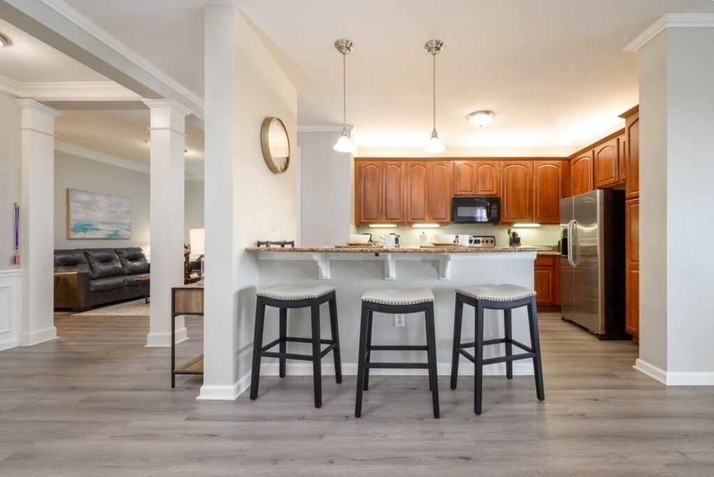 A kitchen with a central island, bar stools, wooden cabinets, and modern appliances.