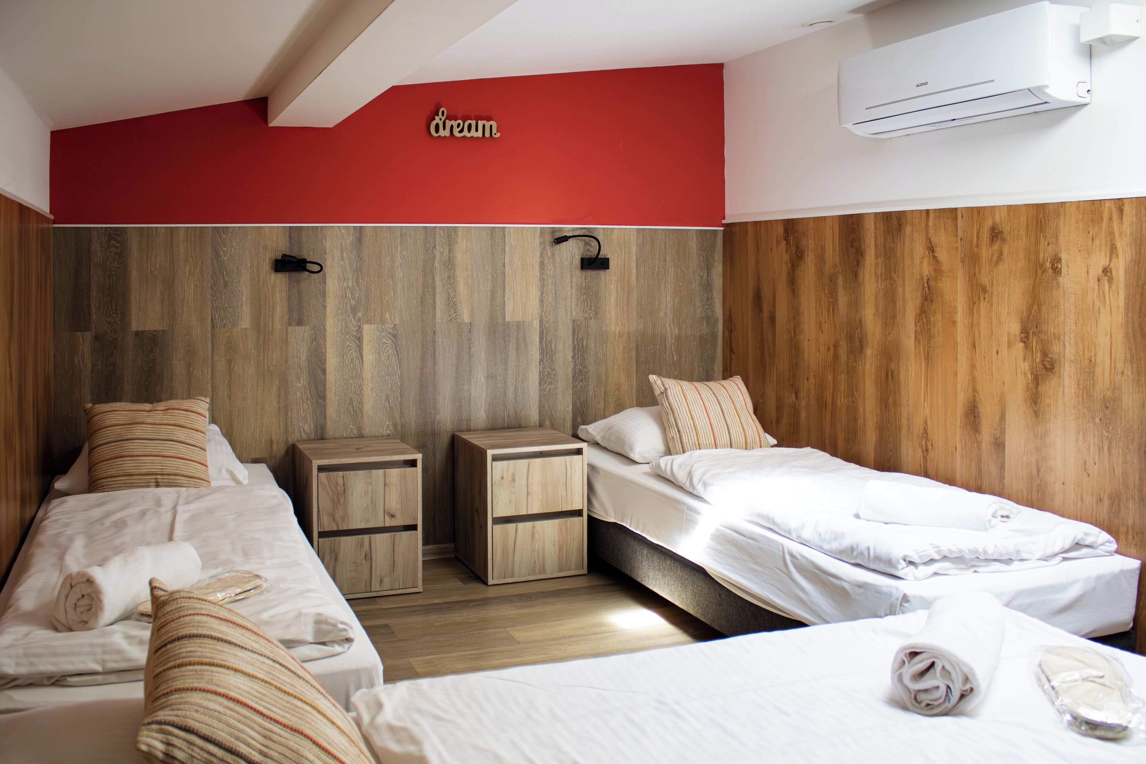 Habitación de hotel con dos camas, paneles de madera en las paredes y un equipo de aire acondicionado.
