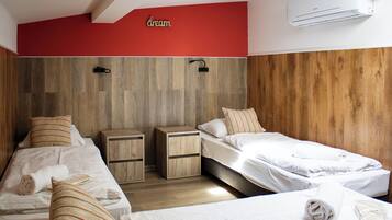 Habitación de hotel con dos camas, paneles de madera en las paredes y un equipo de aire acondicionado.