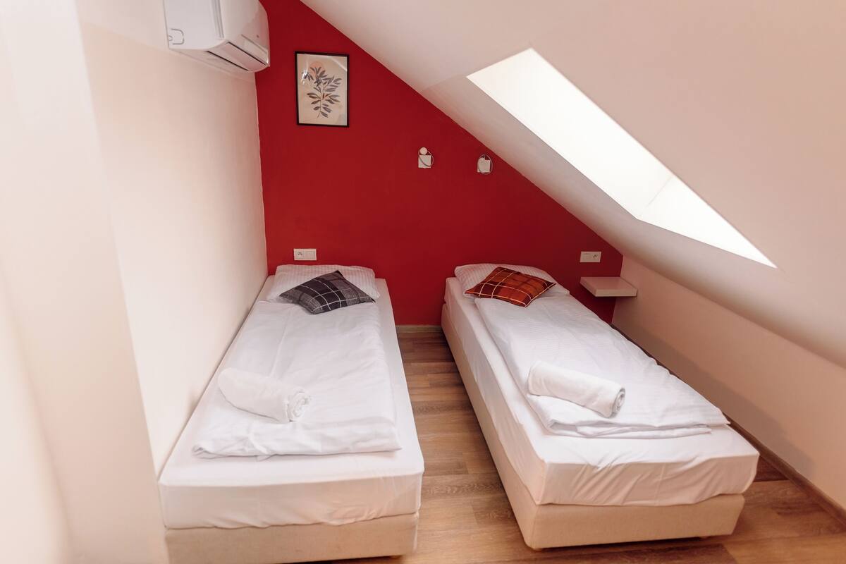 Two single beds in a small room with a sloped ceiling and a skylight.