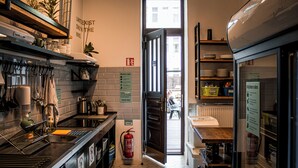 A kitchen with a fire extinguisher, a sign with kitchen rules, and a view of the garden through an open door. - Prague Dream Hostel (Prague)