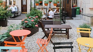 An outdoor seating area with tables and chairs, surrounded by potted plants and a gravel ground. - Prague Dream Hostel (Prague)
