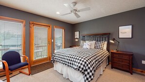 A bedroom with a bed, a chair, a nightstand, and a ceiling fan.