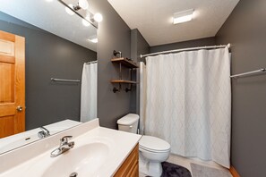 Een badkamer met een witte badkuip, een wit toilet en een douchegordijn.