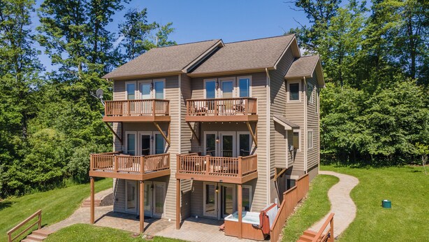 A two-story house with a balcony on each floor, a deck, and a hot tub.