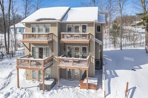 A multi-story building with balconies, a snow-covered roof, and a clear sky. - Cozy Rustic Duplex w/ Hot Tub, Fireplace & Views (McHenry)