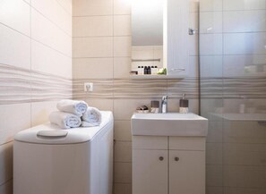 Uma casa de banho moderna com sanita, lavatório e chuveiro.