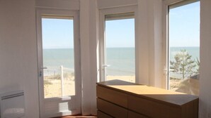 A room with a wooden dresser and a view of the beach through large windows. - Beach House with 180 degree sea views, 6 Bed, 4 Baths, sleeps 10-12 (La Tranche Sur Mer)