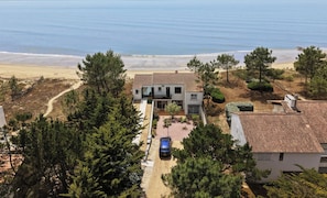 A coastal property with a paved driveway, a parked car, and a view of the beach.