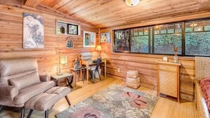 L’intérieur chaleureux d’un chalet avec des murs en bois, un canapé, une table à manger avec des chaises et des œuvres d’art accrochées aux murs.