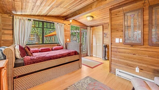 Une cabane en bois chaleureuse, avec un grand lit, une petite table et une fenêtre avec des rideaux.