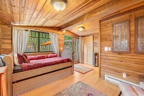 A cozy wooden cabin with a large bed, a small table, and a window with curtains. - Sanctuaire ~ Private Retreat in Monte Rio (Monte Rio)