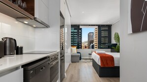 Una cocina moderna con electrodomésticos integrados, un comedor y un dormitorio con vistas a la ciudad.