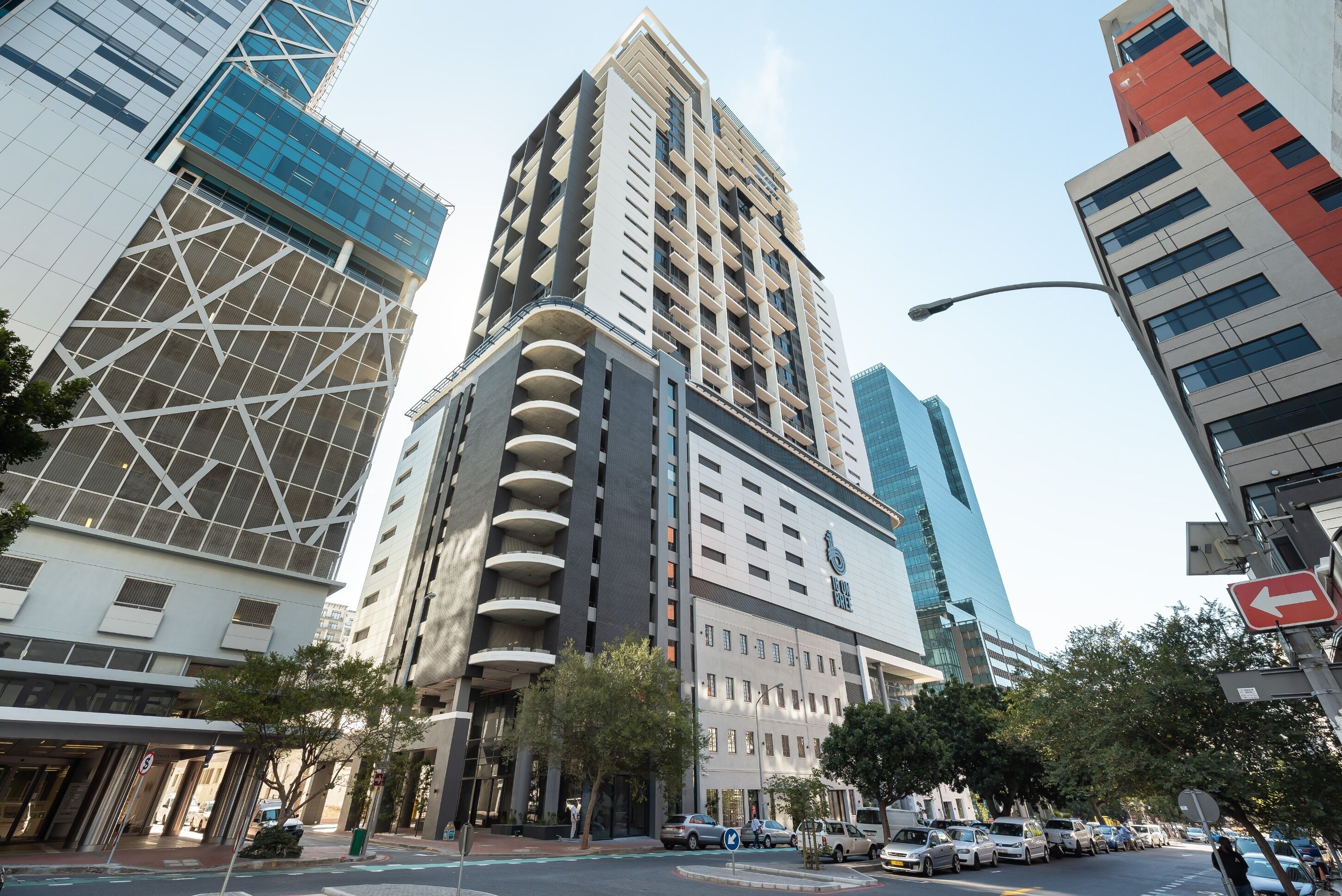 A modern high-rise building with a prominent glass facade, a unique geometric design, and a series of balconies.