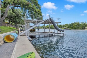 Une structure de toboggan aquatique s’étendant au-dessus d’une étendue d’eau, entourée d’arbres et sous un ciel dégagé.