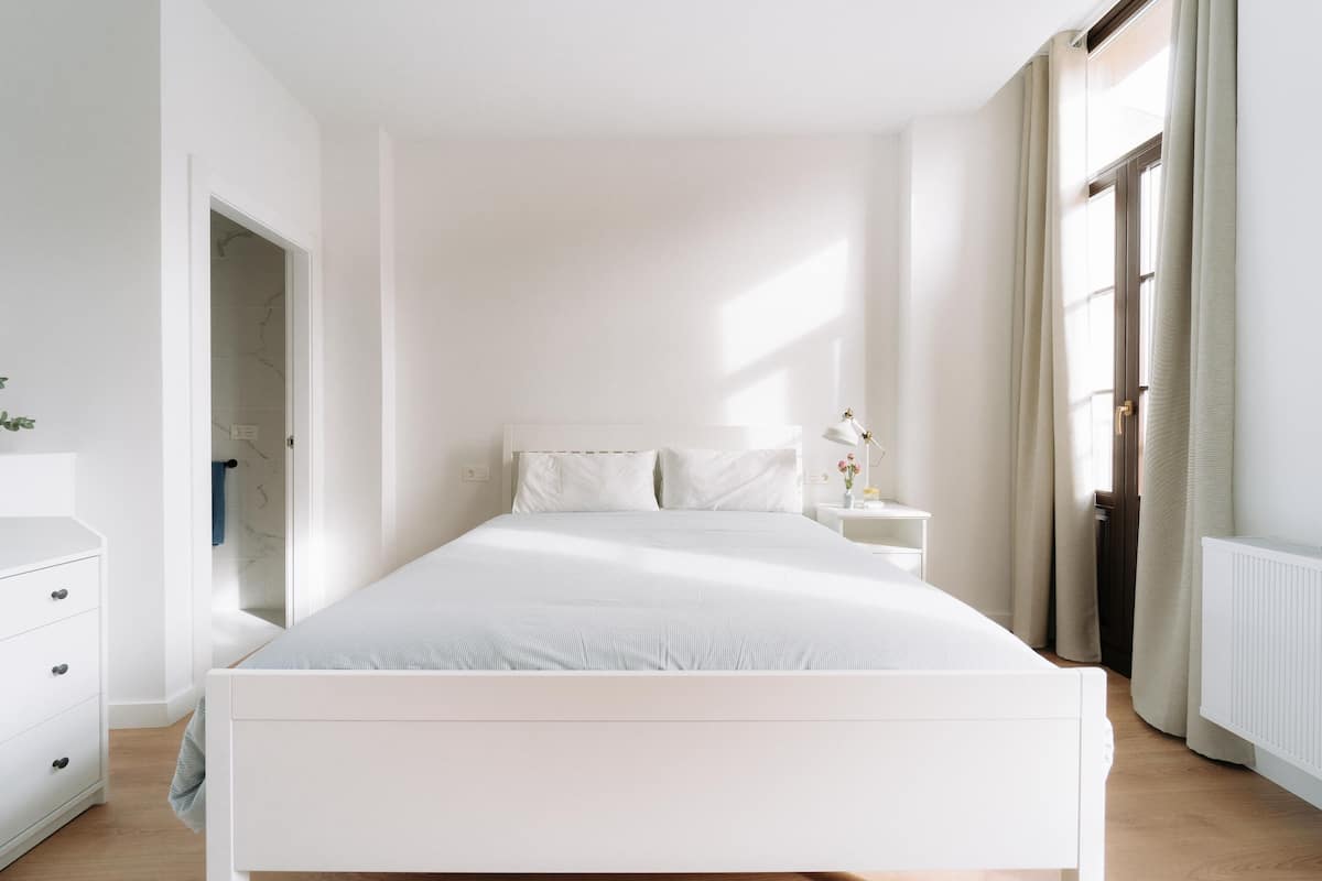 A minimalist bedroom with a large bed, a bedside table, and a nightstand.