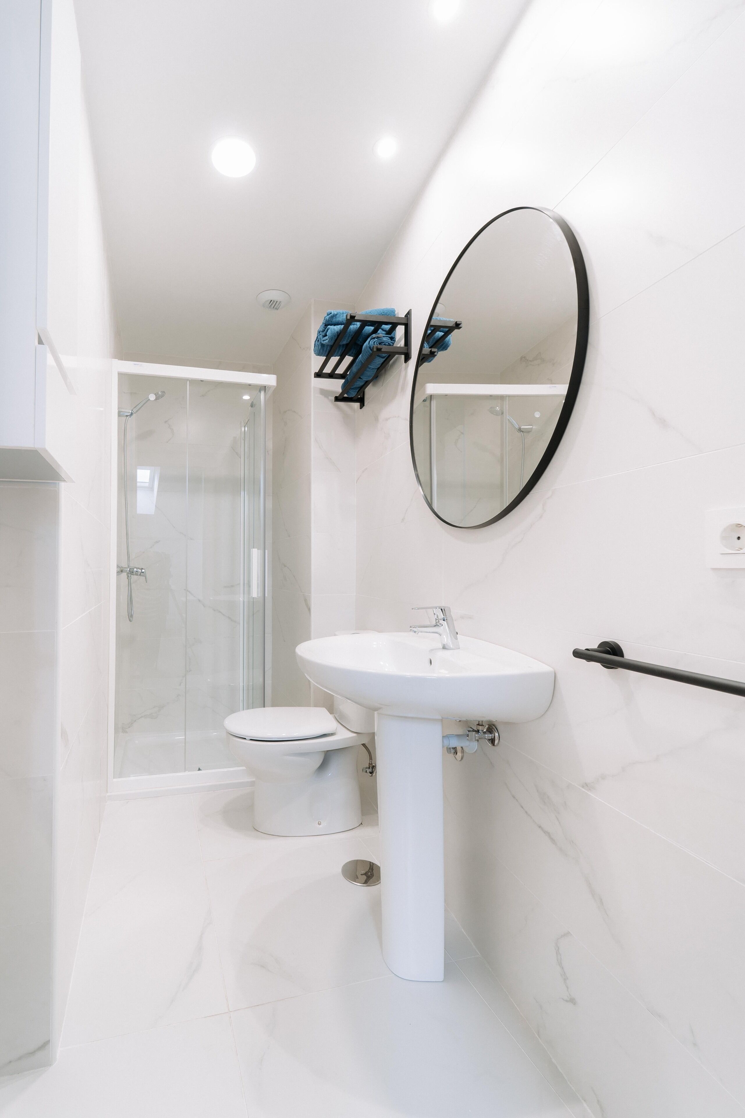A modern bathroom with a white sink, a toilet, and a glass shower enclosure.