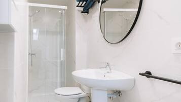 A modern bathroom with a white sink, a toilet, and a glass shower enclosure.