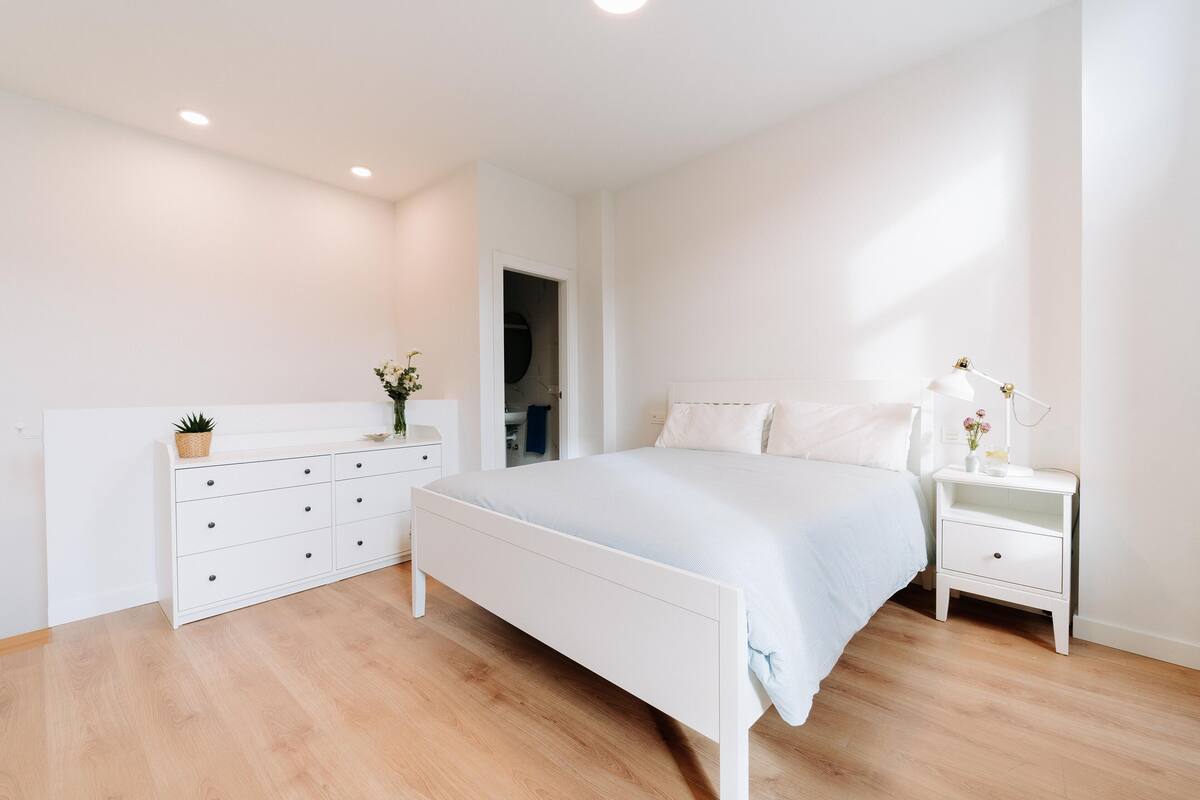 A bedroom with a bed, a dresser, a nightstand, and a door leading to a closet.