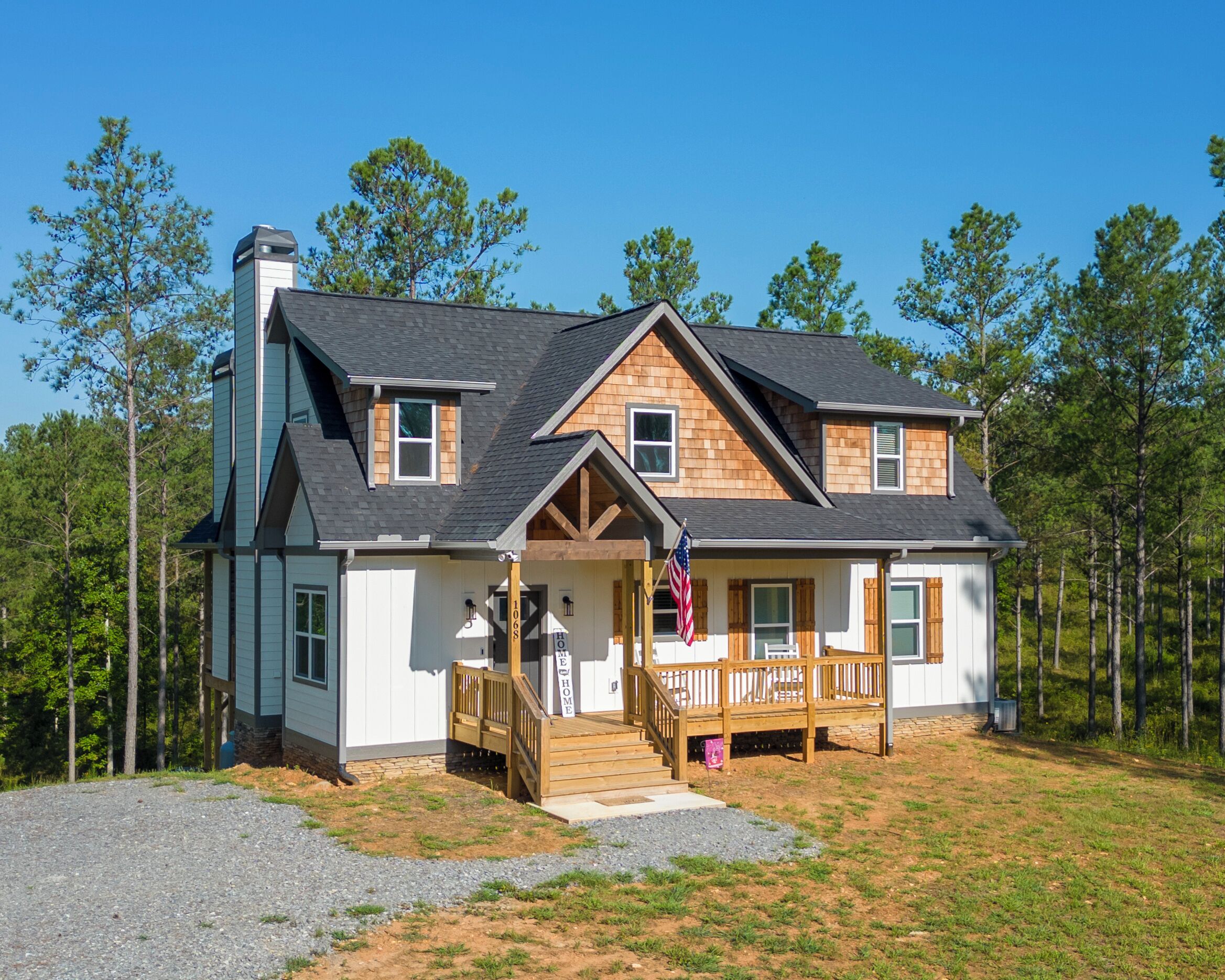 A two-story house with a front porch, a chimney, and a flag.