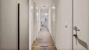 A hallway with white walls and wooden flooring, leading to a kitchen area. - Port Orion - brand new ground floor flat with pool (Nieuwpoort)