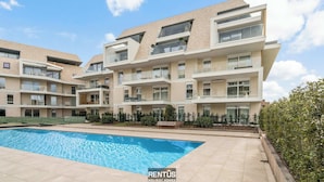 A modern apartment complex with a swimming pool, multiple balconies, and a landscaped garden. - Port Orion - brand new ground floor flat with pool (Nieuwpoort)