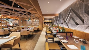 Un restaurant moderne avec des poutres en bois, un long comptoir et un espace repas avec des tables et des chaises.