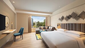 Une chambre d’hôtel moderne dotée d’un grand lit, d’un canapé, d’un bureau et offrant une vue sur la ville.