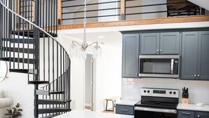 Una cocina moderna con una isla central, electrodomésticos integrados y una escalera de madera.