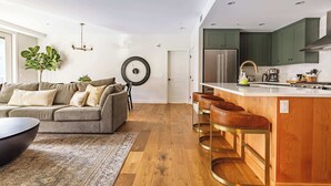 A modern kitchen with green cabinets, a stainless steel refrigerator, and a bar area with stools. - "Inspired Elegance" at Tamarack Lodge (Canmore)