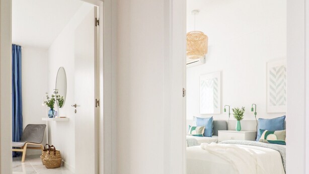 A modern hotel room with a marble floor, a bed with white bedding, a bedside table, and a hanging light fixture.